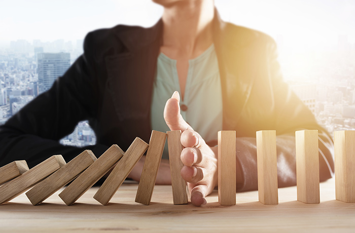 Treffen Sie Ihre eigenen Entscheidungen zu Ihrer Vorsorge. Es ist stets Zeit, mit dem Besseren zu beginnen.
Frau unterbricht eine Kettenreaktion von stürzenden Holzklötzen mit ihrer Hand, ein Symbol für eigene Entscheidungen.